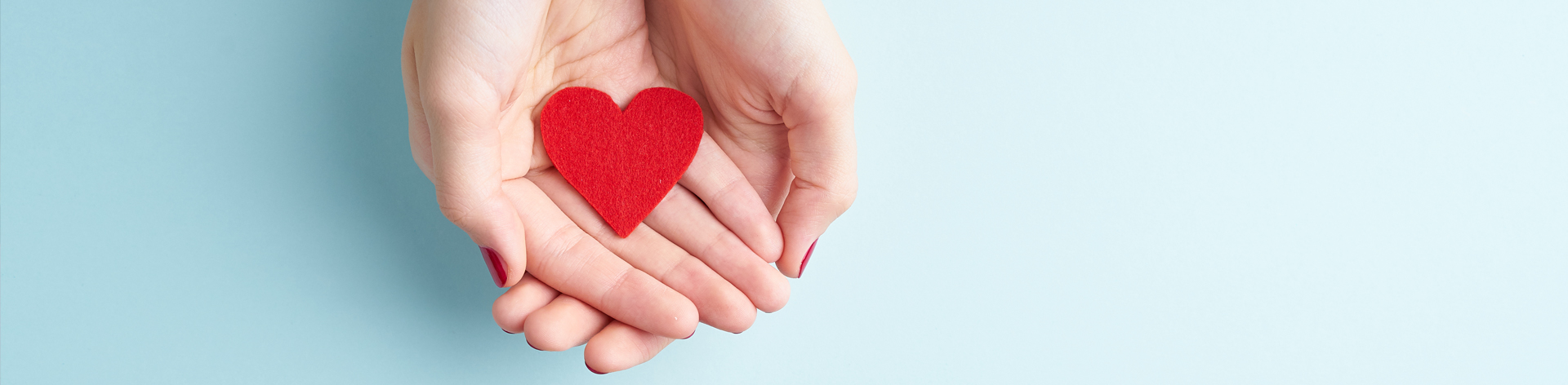 Cupped hands hold a fabric heart