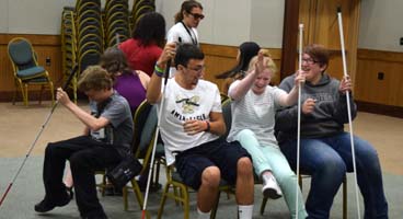 A group of blind students smile while they compete at musical chairs.